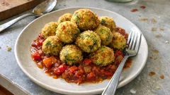 Knusprige Zucchinibällchen in Tomaten-Paprika-Gemüse – außen kross, innen saftig